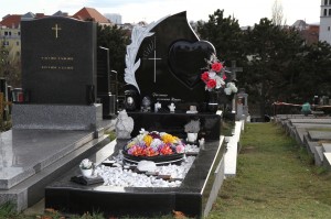 Schwarzes Grab mit Grabstein in Segelform mit einem Herz und weißen Kieselsteinen